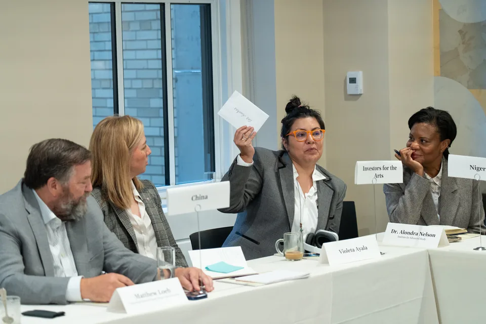 At the simulation table, behind her place card, Violeta Ayala raises an envelope marked Las Awichas.